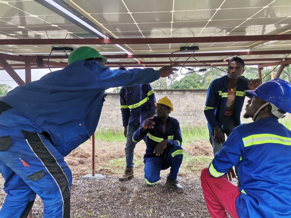 A trainer explaining the cabling under a solar array to a group of trainees