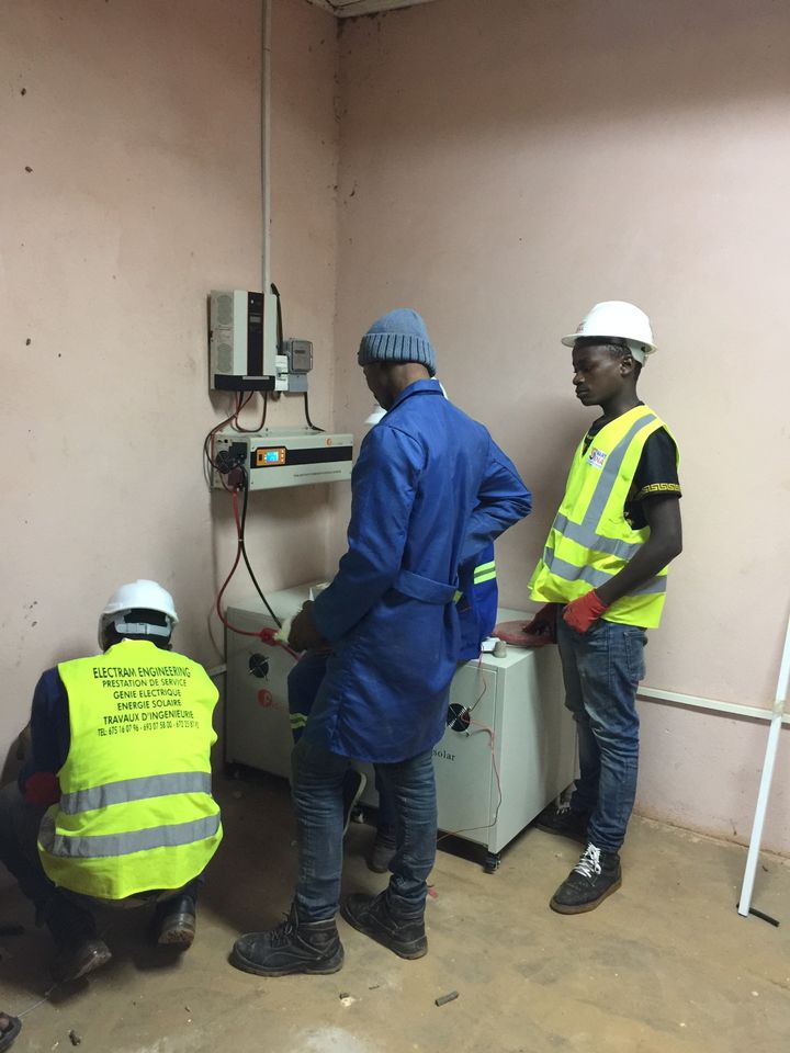 Trainees connecting the cables of an inverter and battery cabinet indoors
